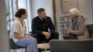 Sicherheitskraft im respektvollen Gespräch mit Pflegekraft und älterer Frau