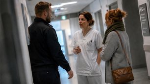 Ruhige Gesprächssituation zwischen Sicherheitskraft, Pflegekraft und Besucherin